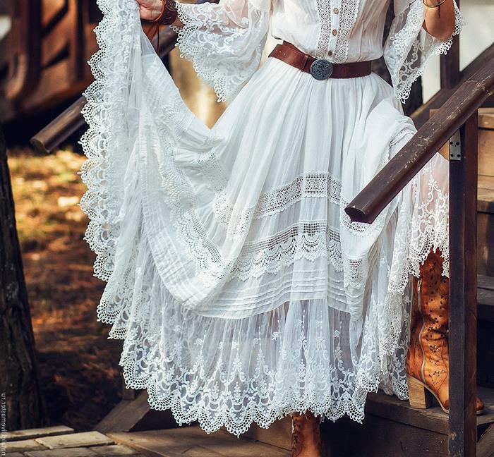 boho style maxi dress white with lace hem sleeves and inserts worn with brown leather belt with iron buckle by woman standing on wooden stairs | Western Boho style inspiration